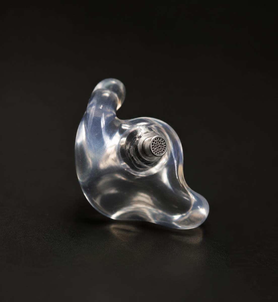 Close-up of a clear custom earplug fitted with an acoustic filter